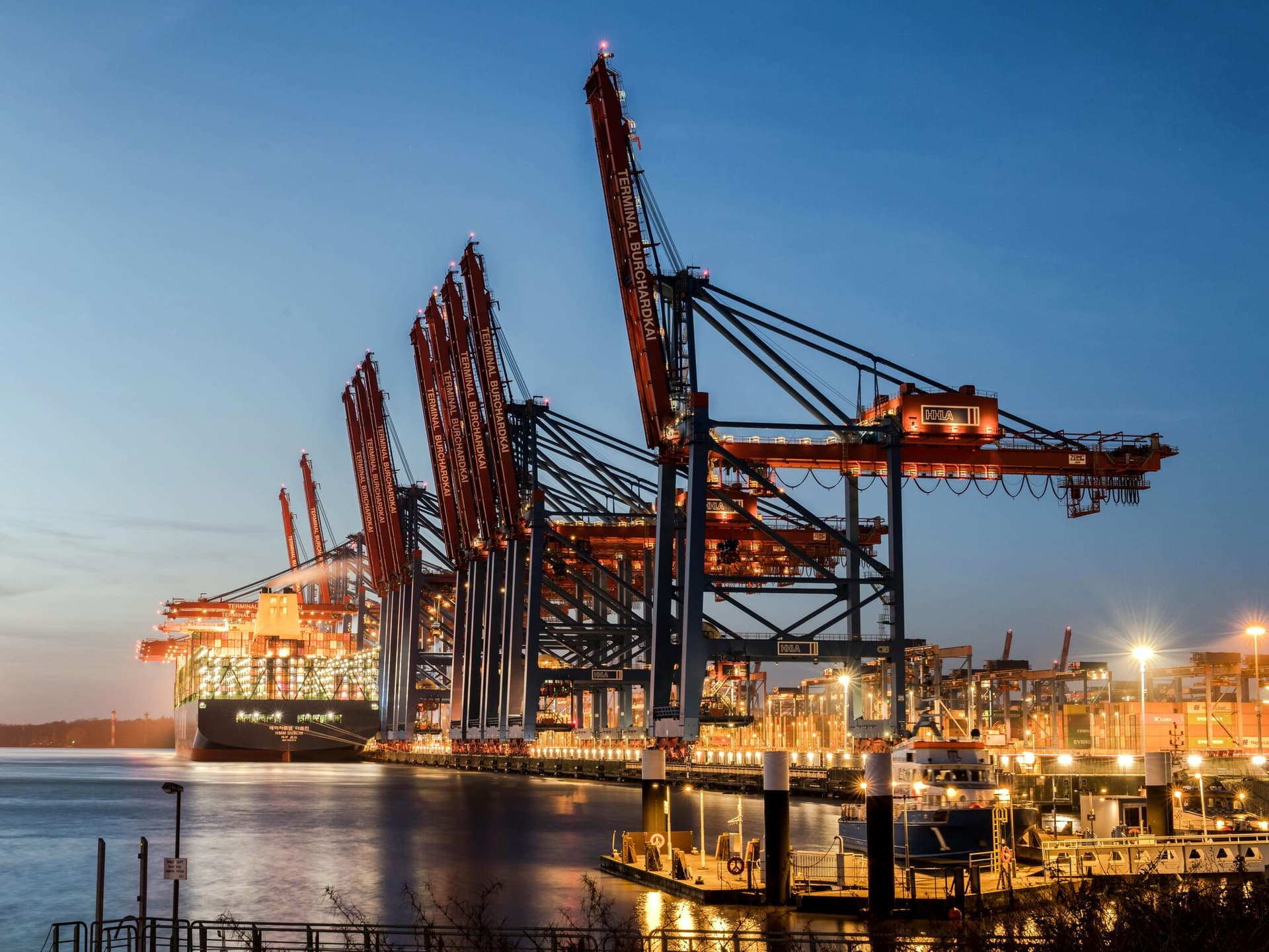 Grúas pórtico de una terminal de contenedores iluminadas sobre un buque a la hora azul